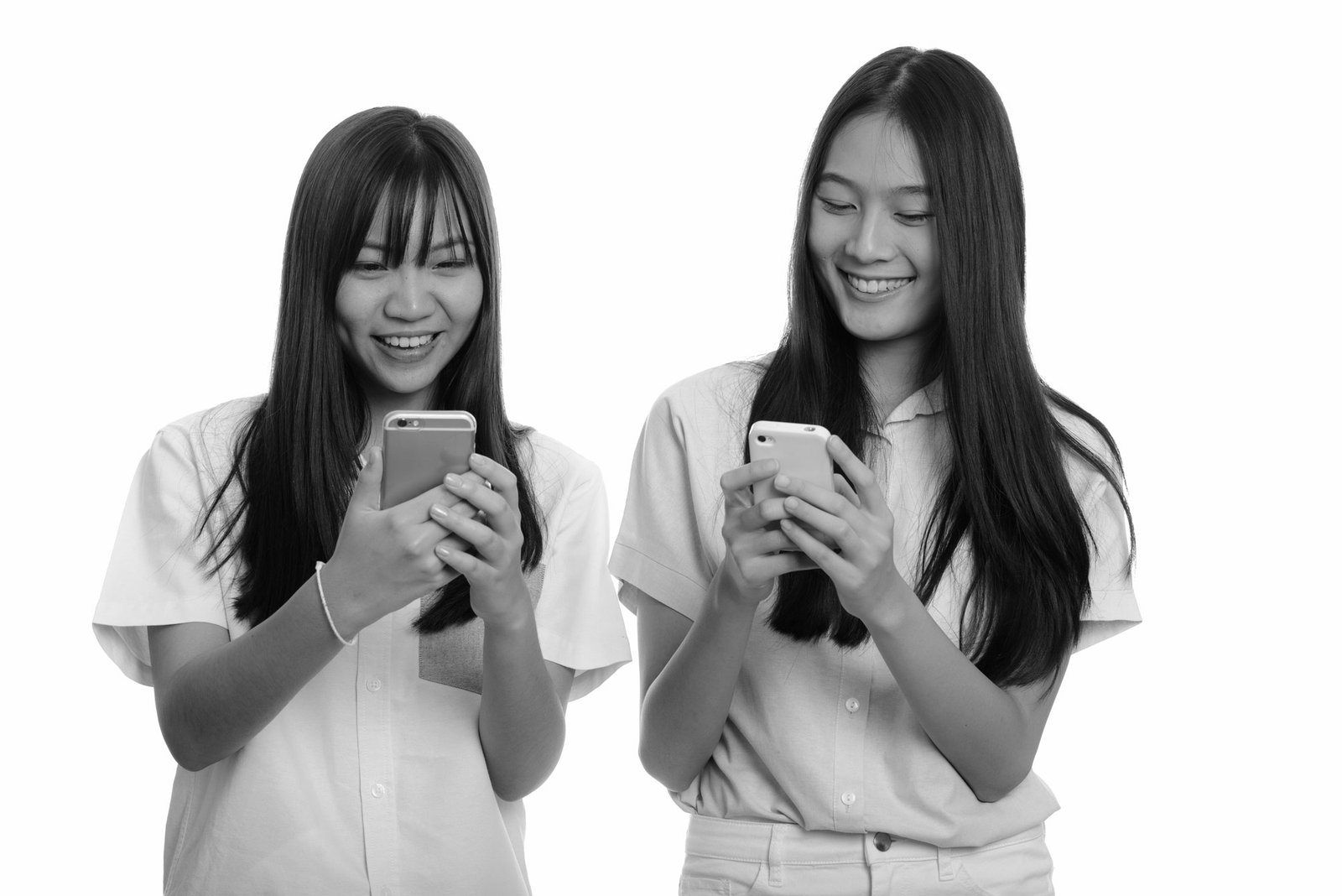 Two teenage girls smiling at phones