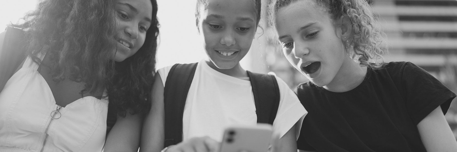Three teenage girls looking at a phone together